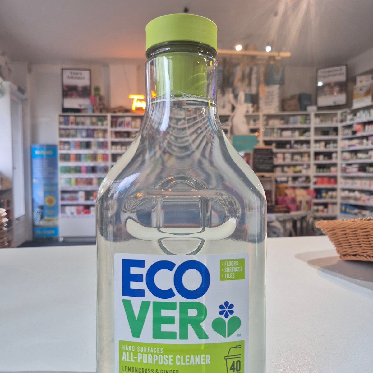 Clear bottle with green cap and Eco Ver label on a blurred indoor background