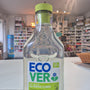 Clear bottle with green cap and Eco Ver label on a blurred indoor background