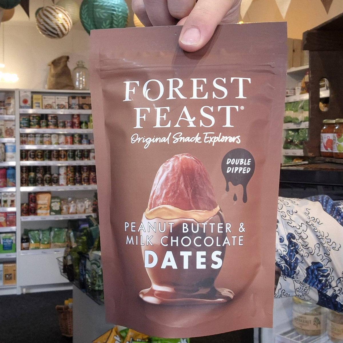 Hand holding a 'Forest Feast' snack package in a store setting