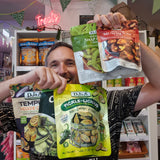 A smiling man holds up five bags of DJ&A