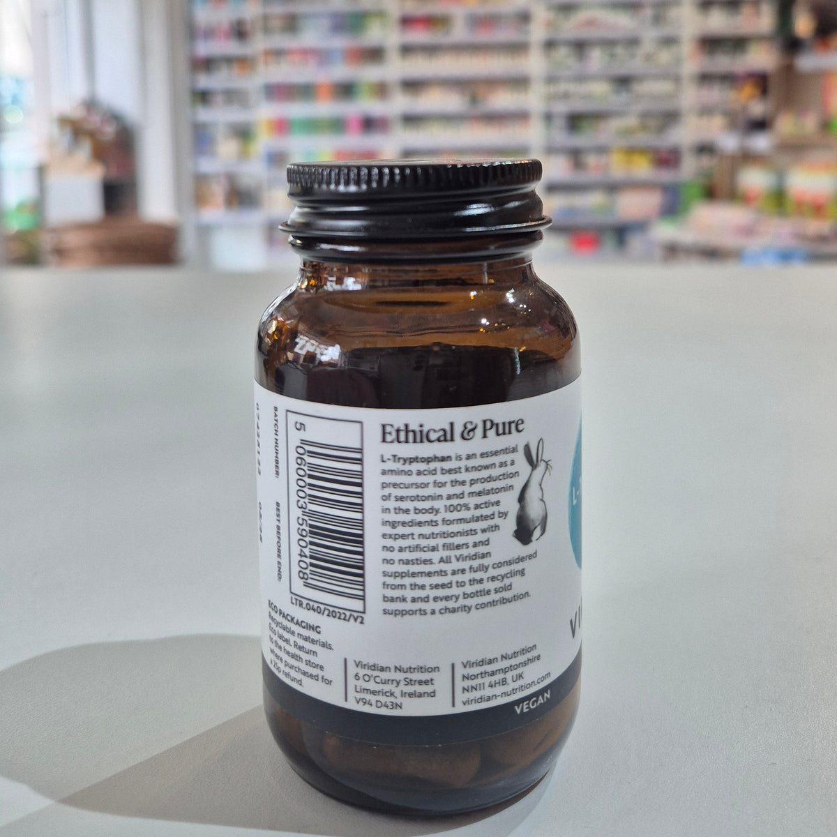 Bottle with label on a white surface, blurred background of shelves with products