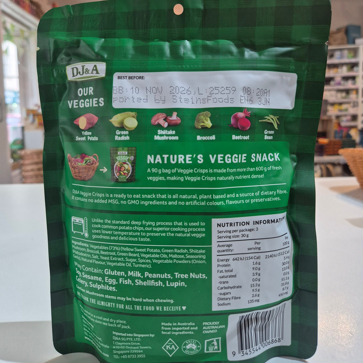 Green package of DJ&A Veggie Crisps with a bowl of colourful vegetables package with text and branding on a white surface