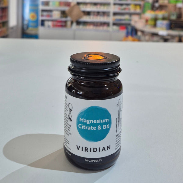 Viridian supplement bottle on a white surface with a blurred background of books and shelves.