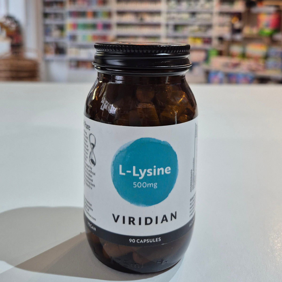Bottle of Viridian L-Lysine supplement on a white surface with a blurred background