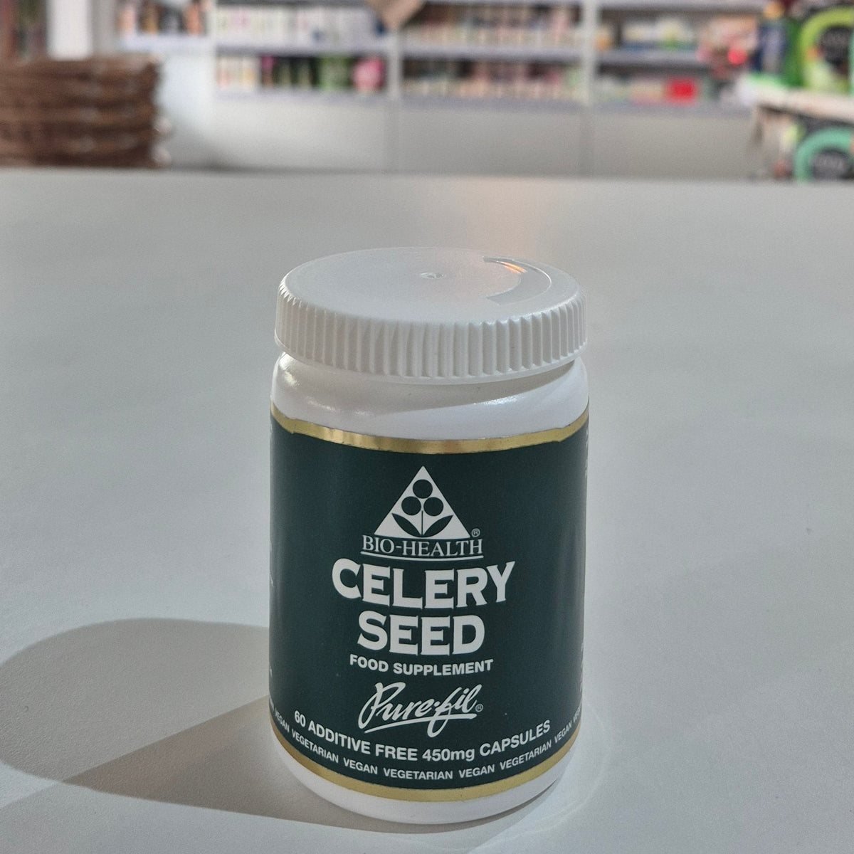 Jar of Bio-Health celery seed supplement on a table with a blurred background