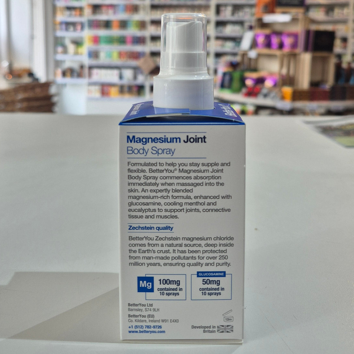 Magnesium Joint Body Spray packaging with a blurred store background