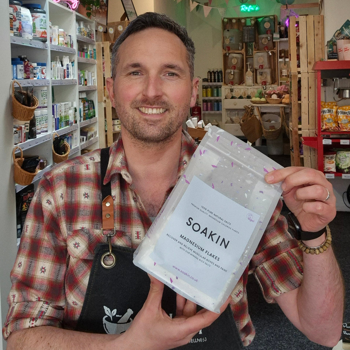 Man holding a package of 'Soakin' magnesium flakes in a store setting