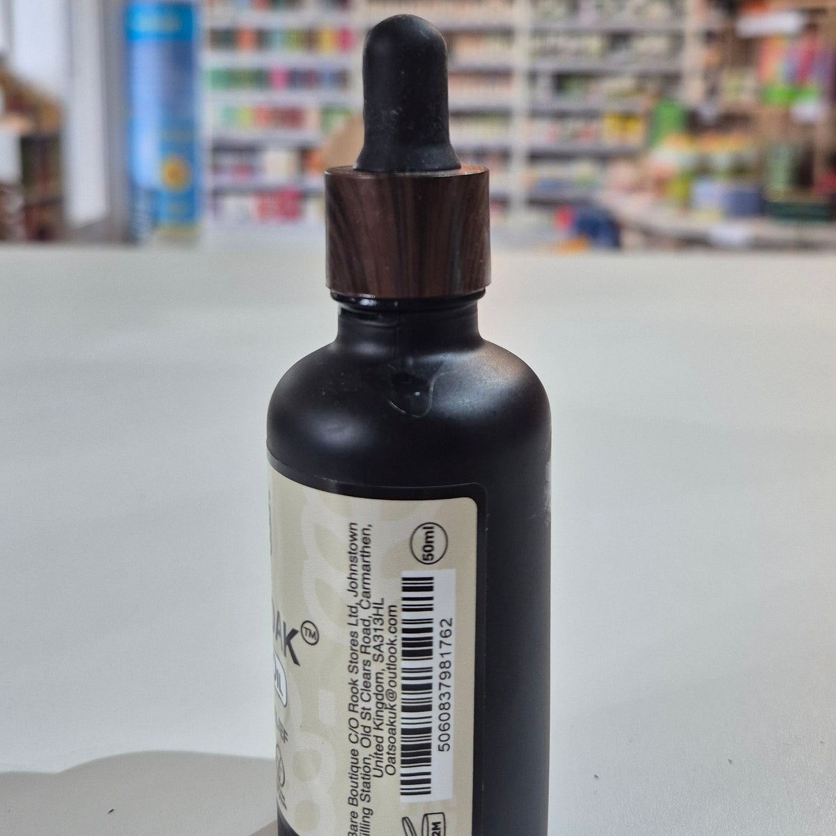 Black dropper bottle with a label on a white surface, blurred background