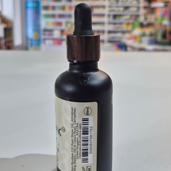 Black dropper bottle with a label on a white surface, blurred background