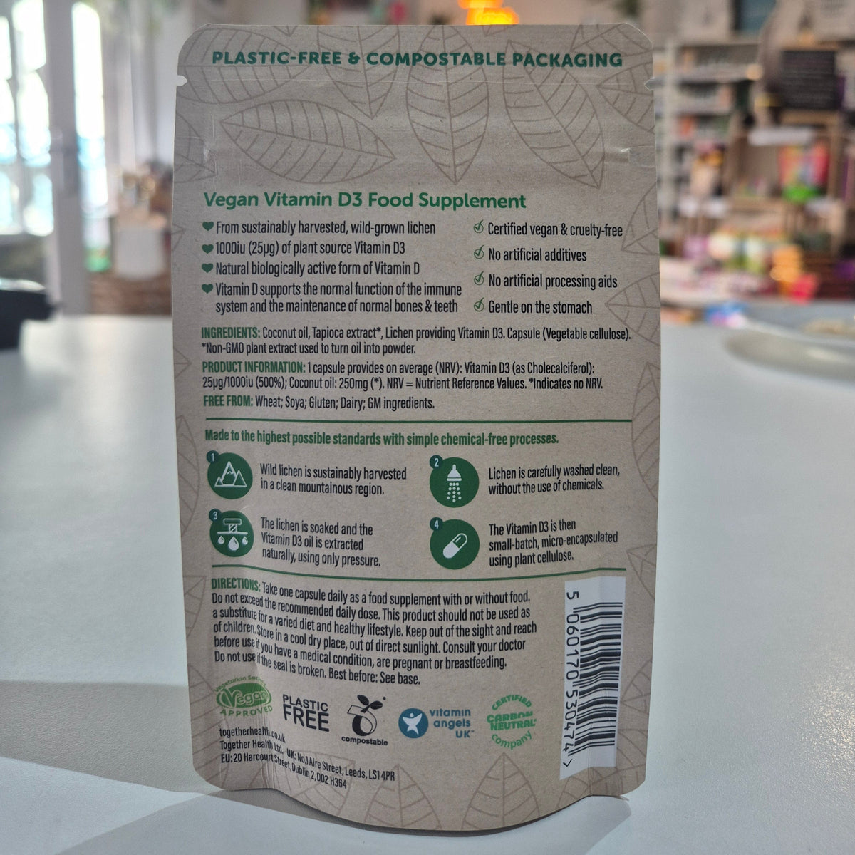 Back of a Together Health vegan vitamin D3 supplement packaging with text and icons on a blurred background