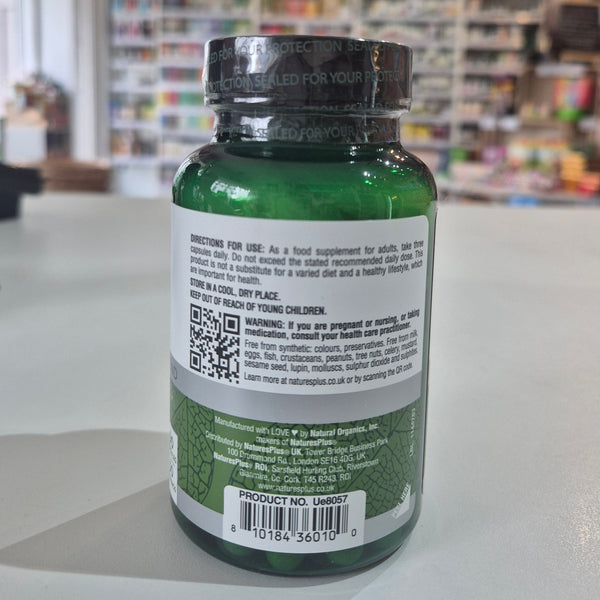 Green supplement bottle with label and QR code on a blurred store background