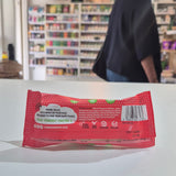 A packaged meringue bar in a red and white wrapper labeled 'Flower & White' and 'Chocolate Dipped Strawberry', placed on a white surface with a blurred store shelf background.