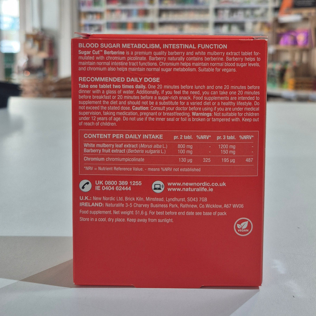 Red supplement box with text on a blurred indoor background