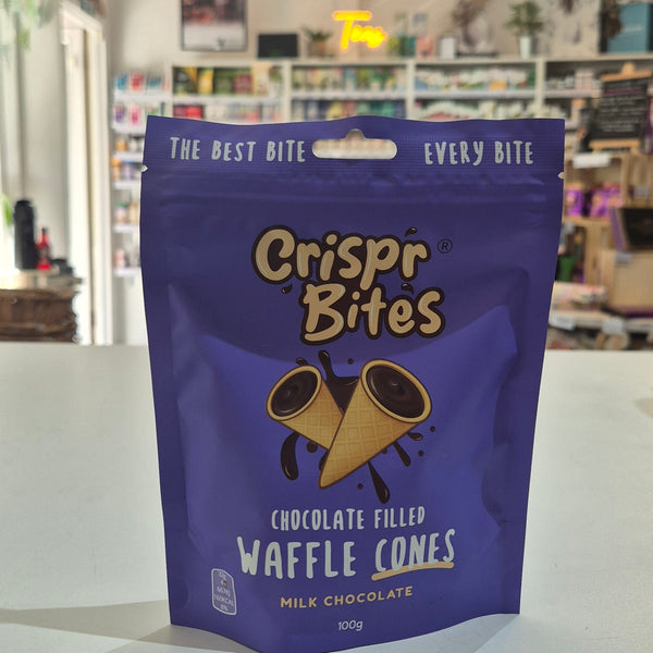 A purple stand-up pouch of Crispr Bites Milk Chocolate Filled Waffle Cones on a white countertop in a blurred retail shop setting.