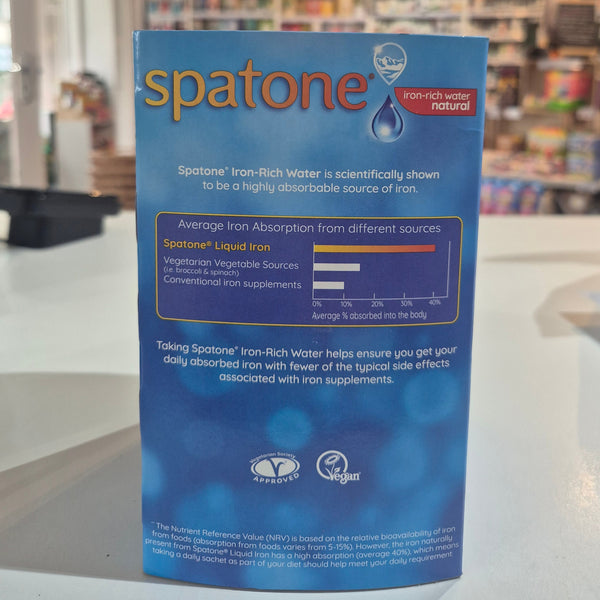 Spatone vitamin supplement packaging held in front of a blurred store interior.