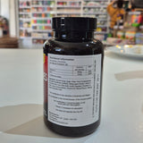 Black supplement bottle with nutritional label on a white surface, blurred store background