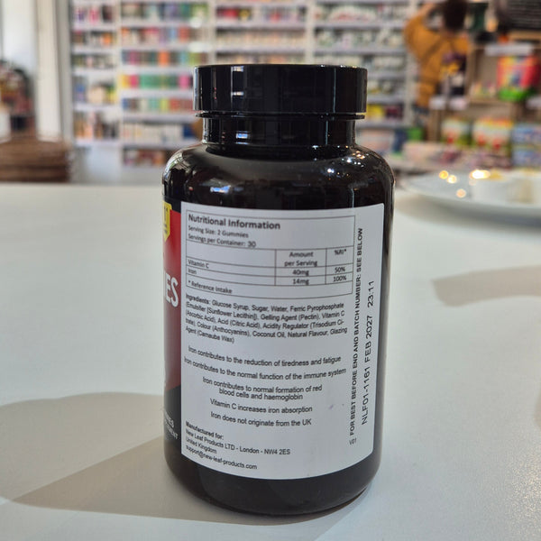 Black supplement bottle with nutritional label on a white surface, blurred store background