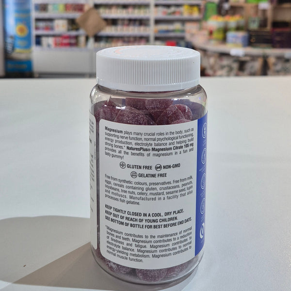 Bottle of magnesium gummies with a label held in front of a store shelf.