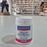 Lamberts Vitamins D3 & K2 supplement container on a table with a blurred store background