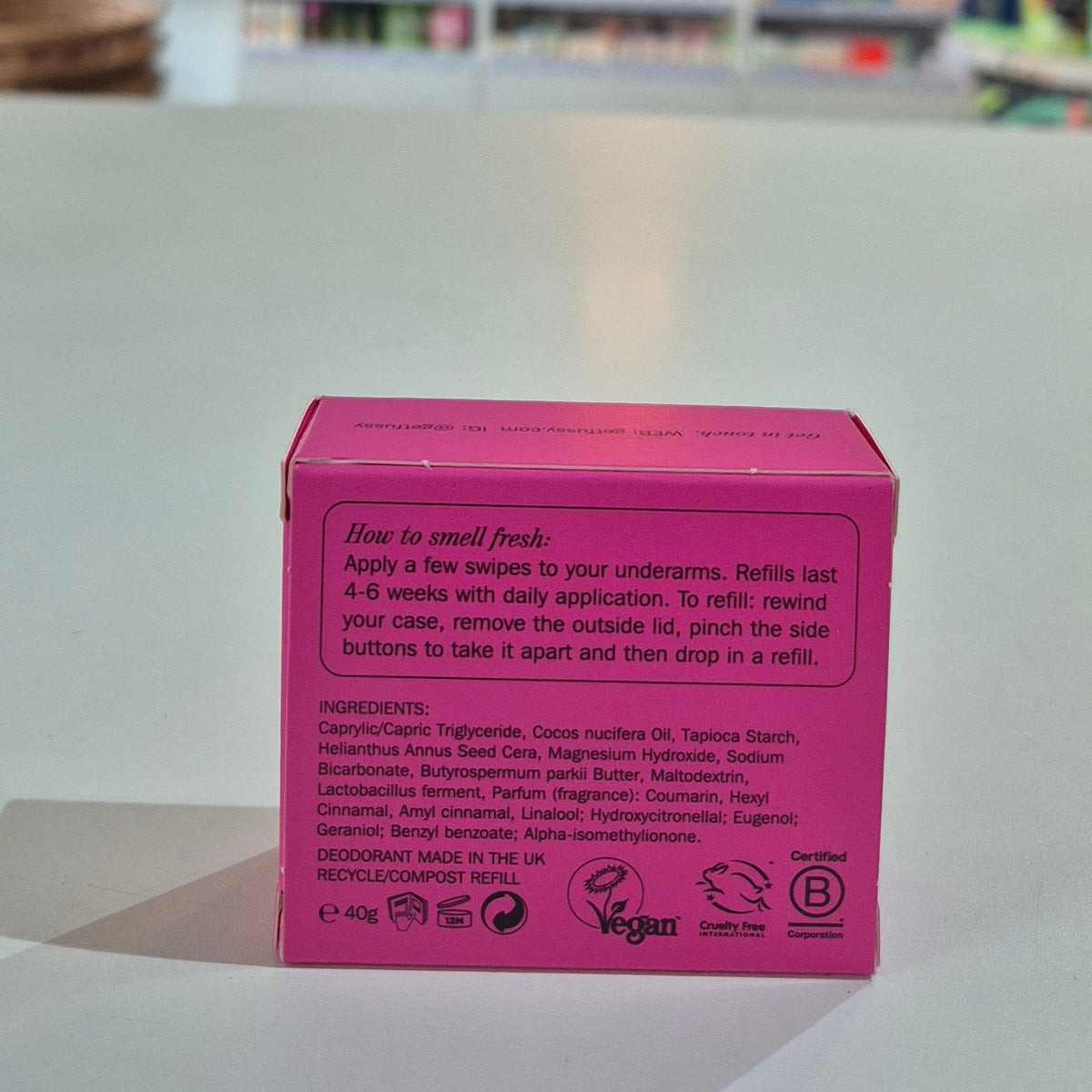Pink deodorant box with text on a light gray surface