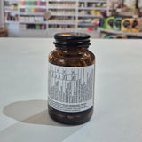 Brown supplement bottle with label on a white surface, blurred store shelves in the background