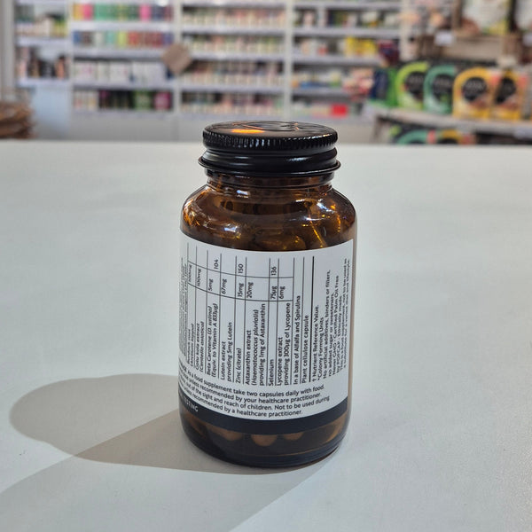 Brown supplement bottle with label on a white surface, blurred store shelves in the background