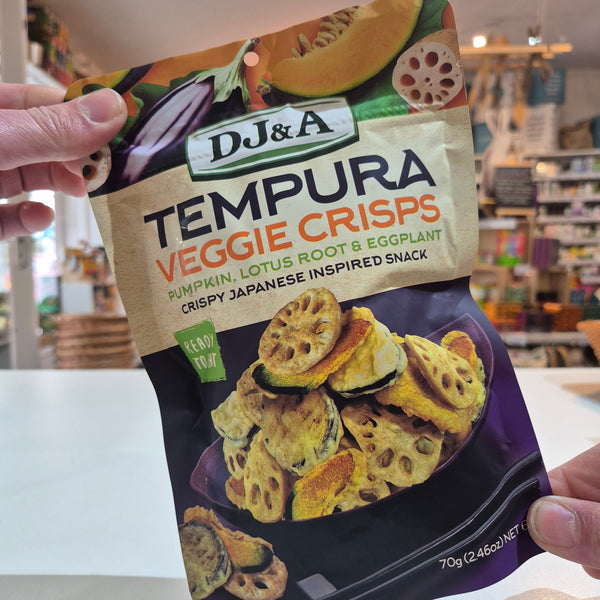 Packaged tempura veggie crisps held by a person in an indoor setting.