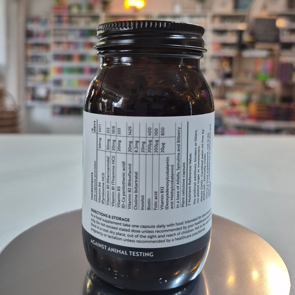 Jar of Viridian High Six B6 B Complex supplement on a counter with a blurred store background. Brown glass supplement bottle with label on a reflective surface in a store setting