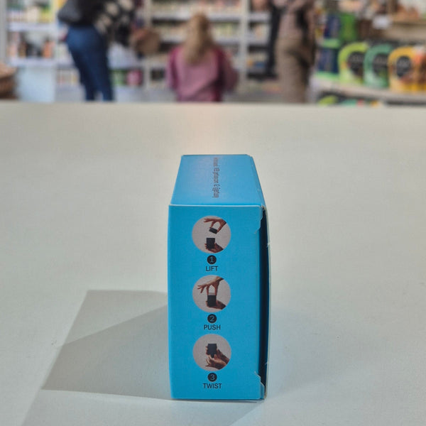 Fussy compostable deodorant refill packaging with a store in the background. Blue box with icons and text on a light gray surface, blurred background of people and products.