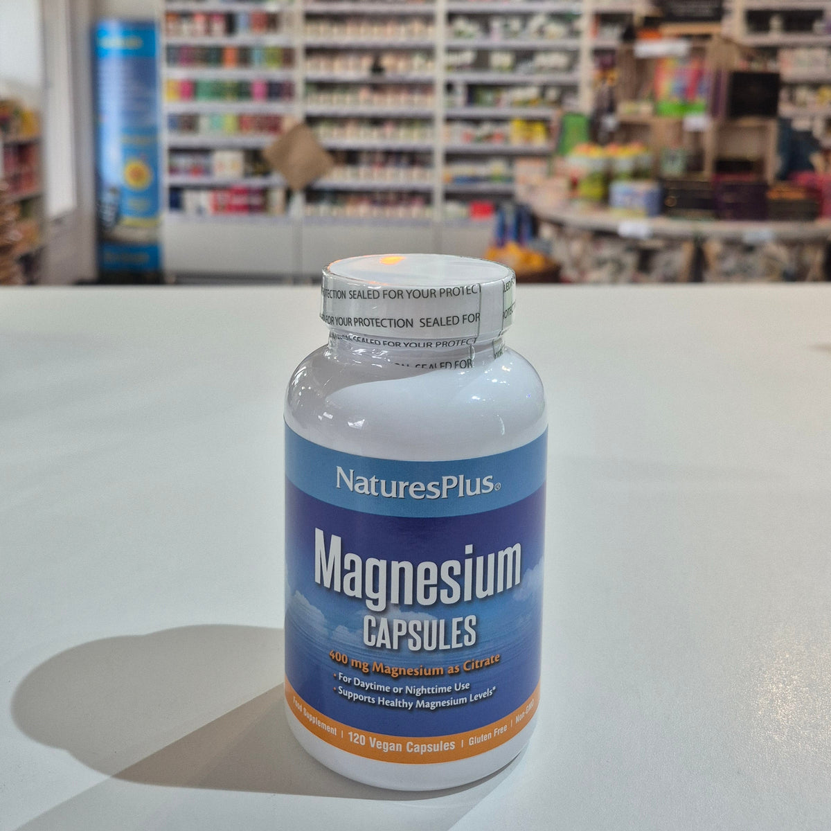 Nature's Plus Magnesium capsules bottle with a blurred store interior in the background
