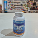 Nature's Plus Magnesium capsules bottle with a blurred store interior in the background