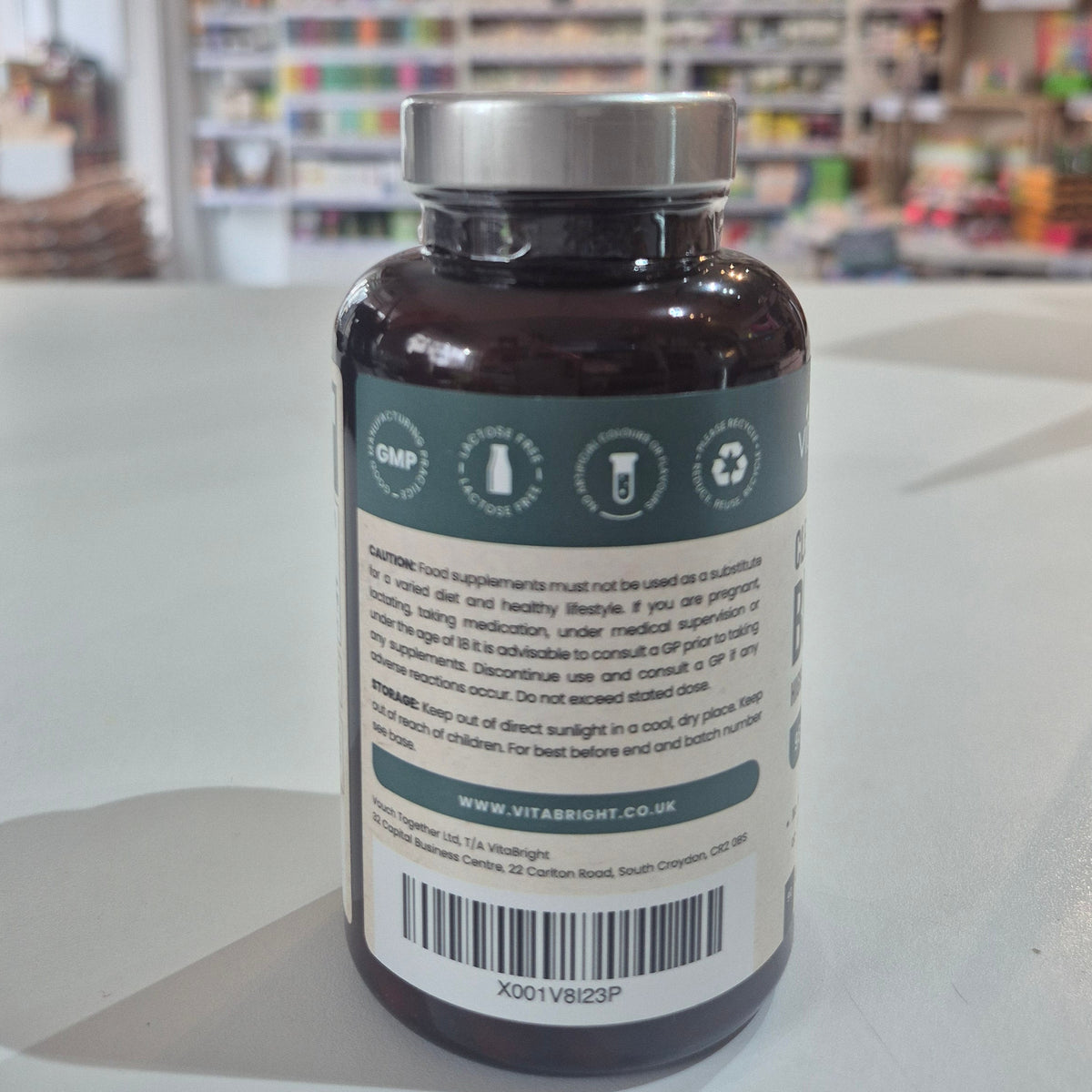 Vitamins bottle with label on a white surface, blurred store background