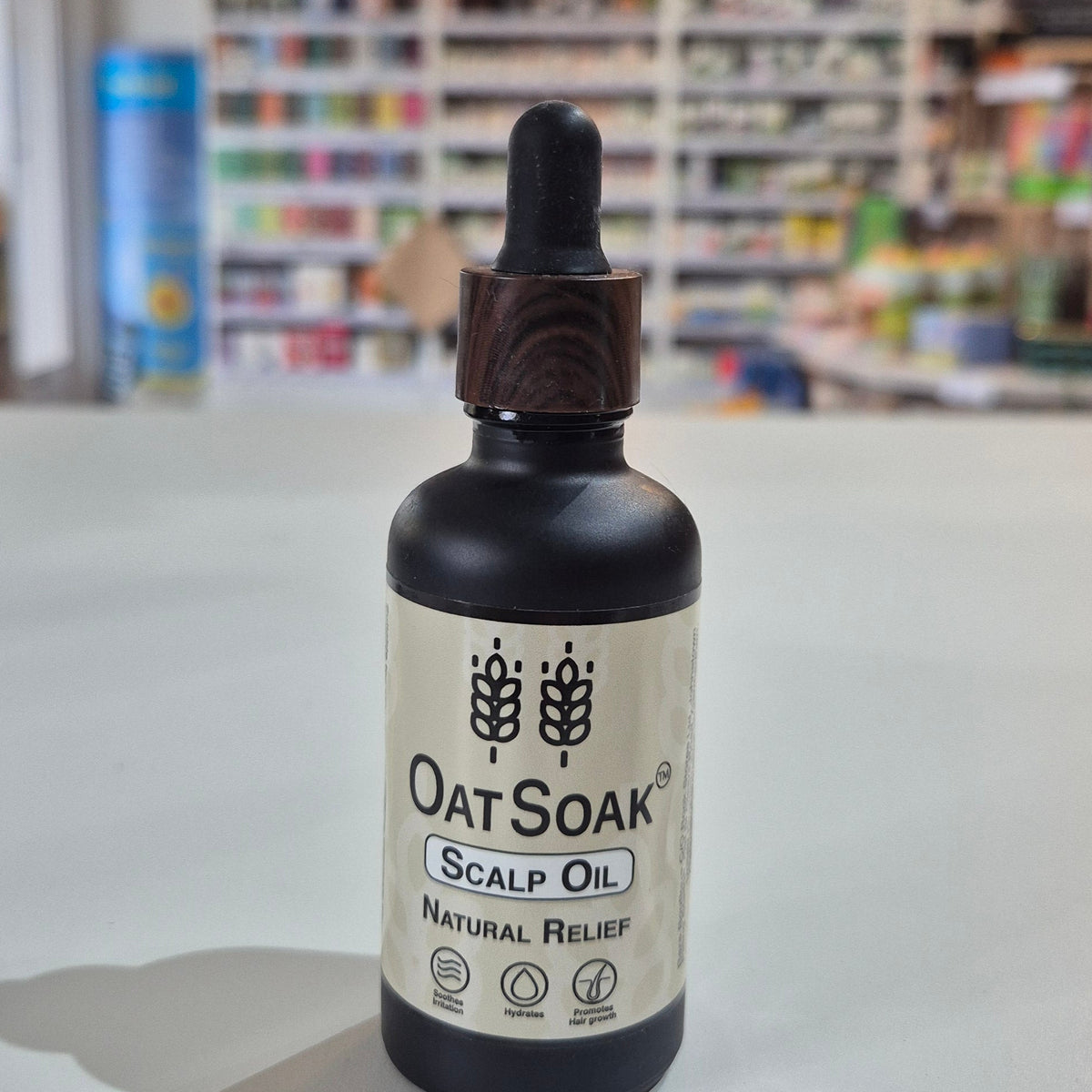 Bottle of Oatsoak Scalp Oil on a white surface with a blurred store background