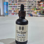 Bottle of Oatsoak Scalp Oil on a white surface with a blurred store background