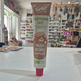 A tube of Tartex Vegetarian Pate Mushrooms on a white countertop with a blurred grocery store background.