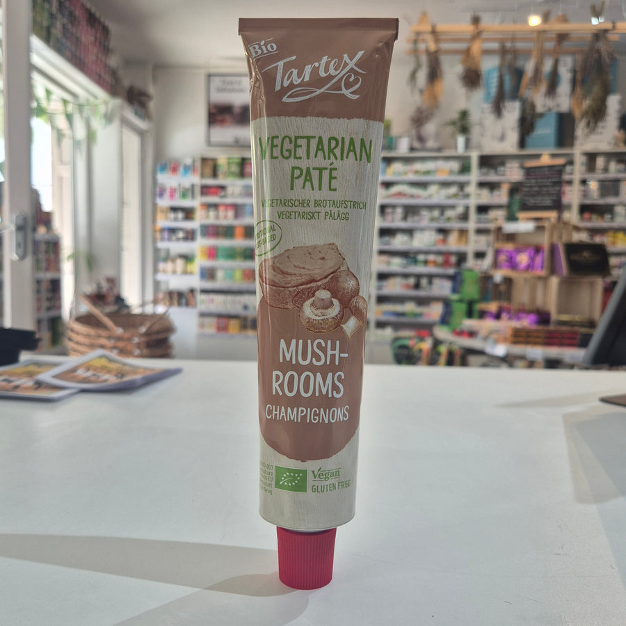 A tube of Tartex Vegetarian Pate Mushrooms on a white countertop with a blurred grocery store background.