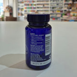 Blue supplement bottle with label on a white surface, blurred store background