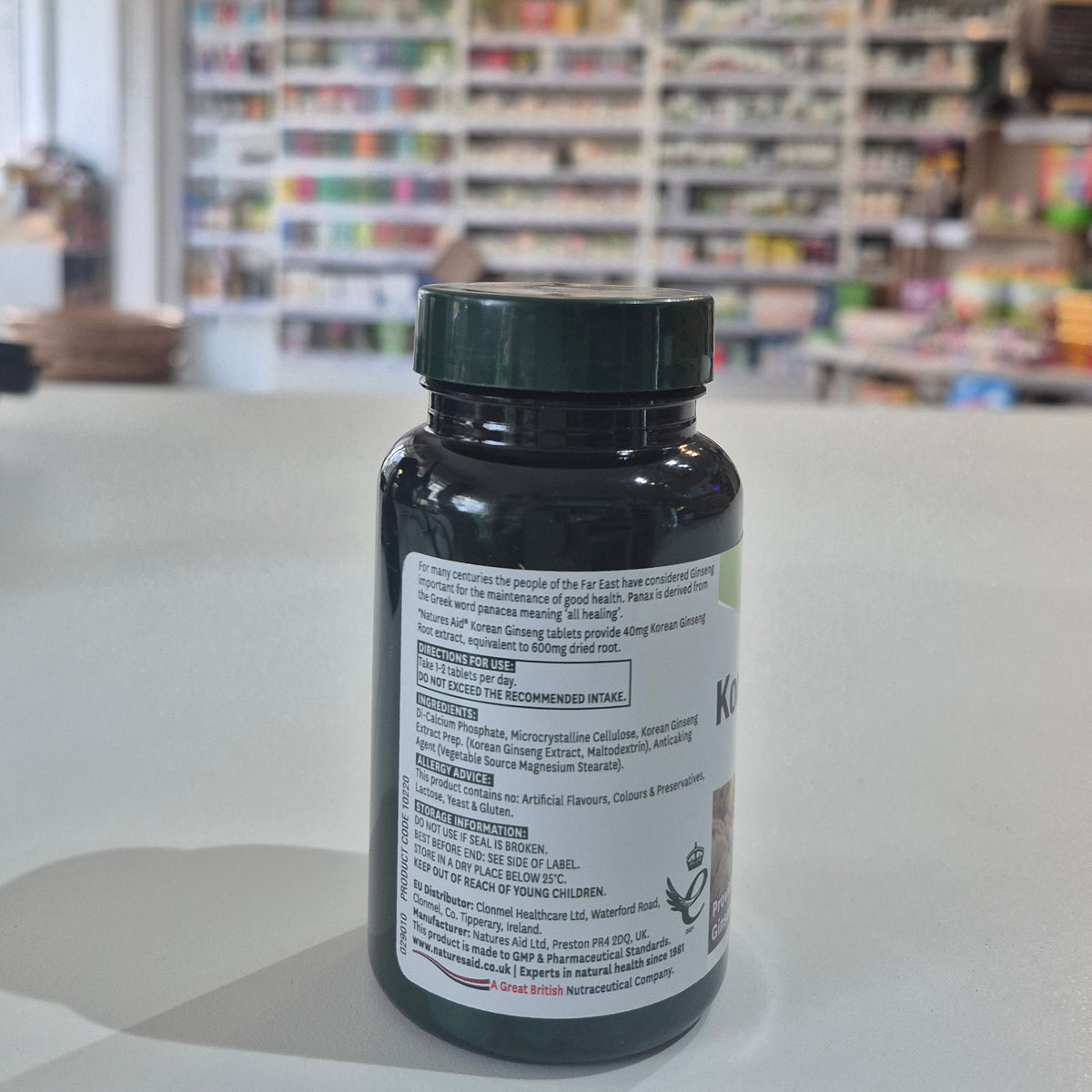 Bottle with label on a white surface with a blurred background of shelves with products.