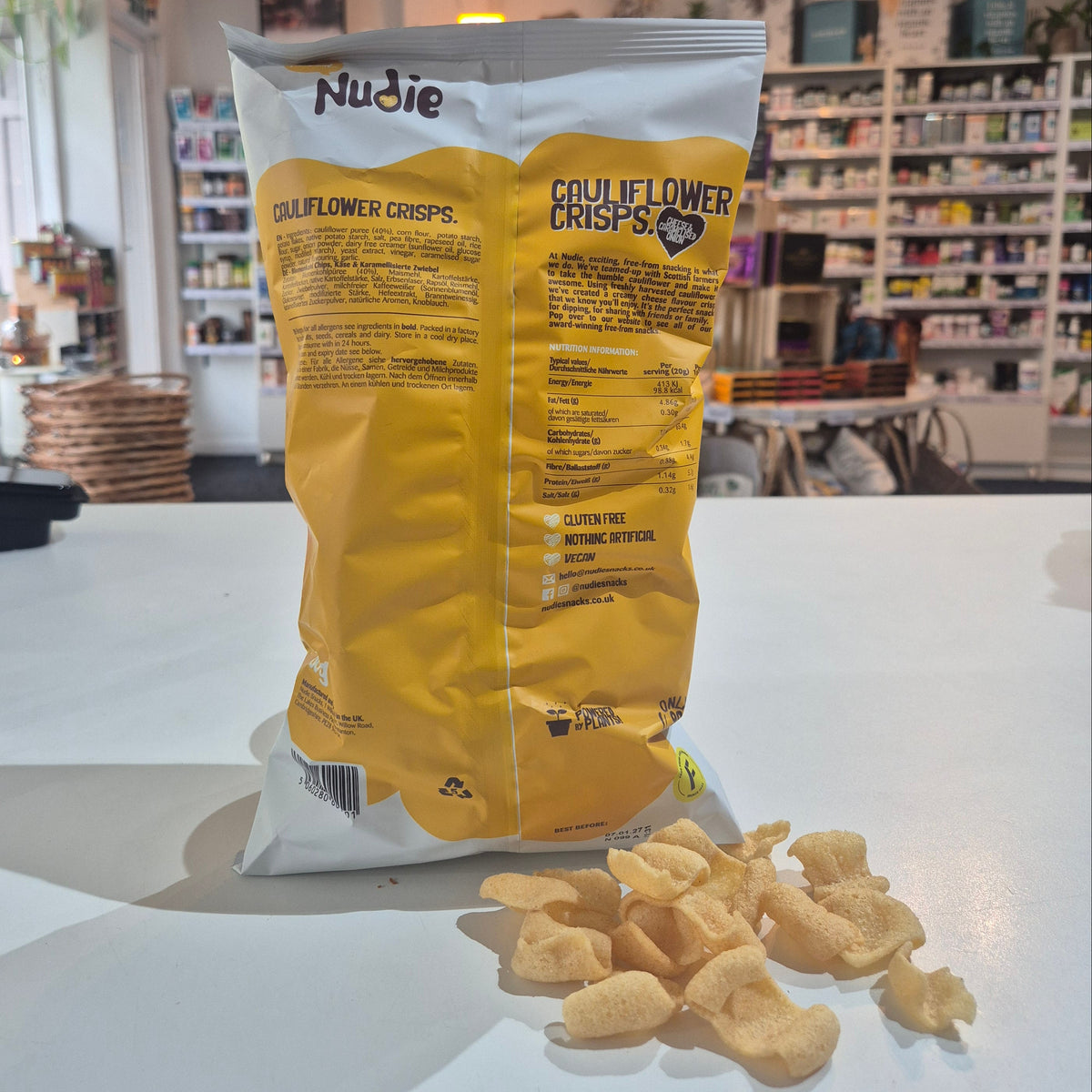 Yellow and white snack bag with 'Nudie cauliflower crisps' branding on a white surface.