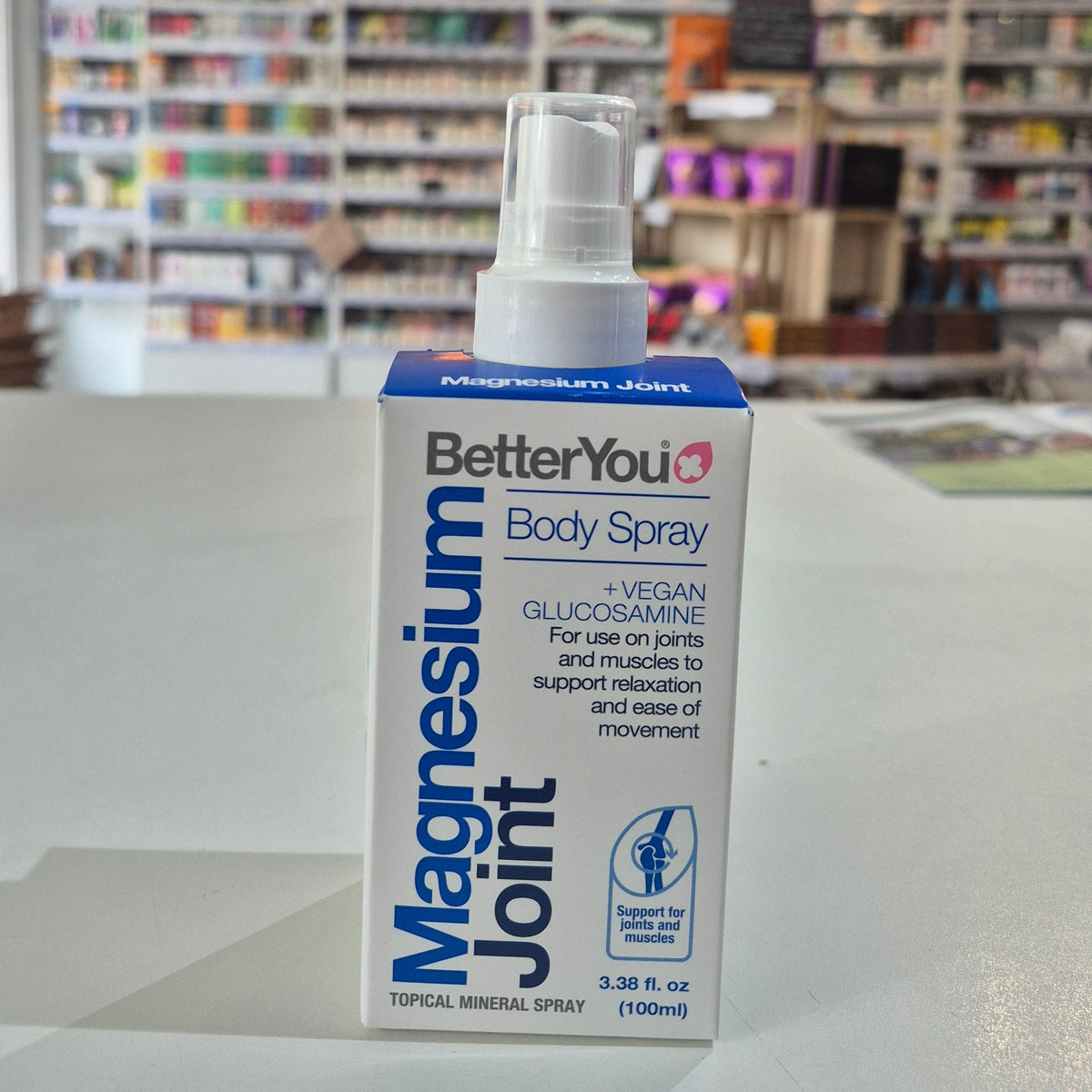 BetterYou Magnesium Joint Body Spray bottle on a surface with a blurred store background