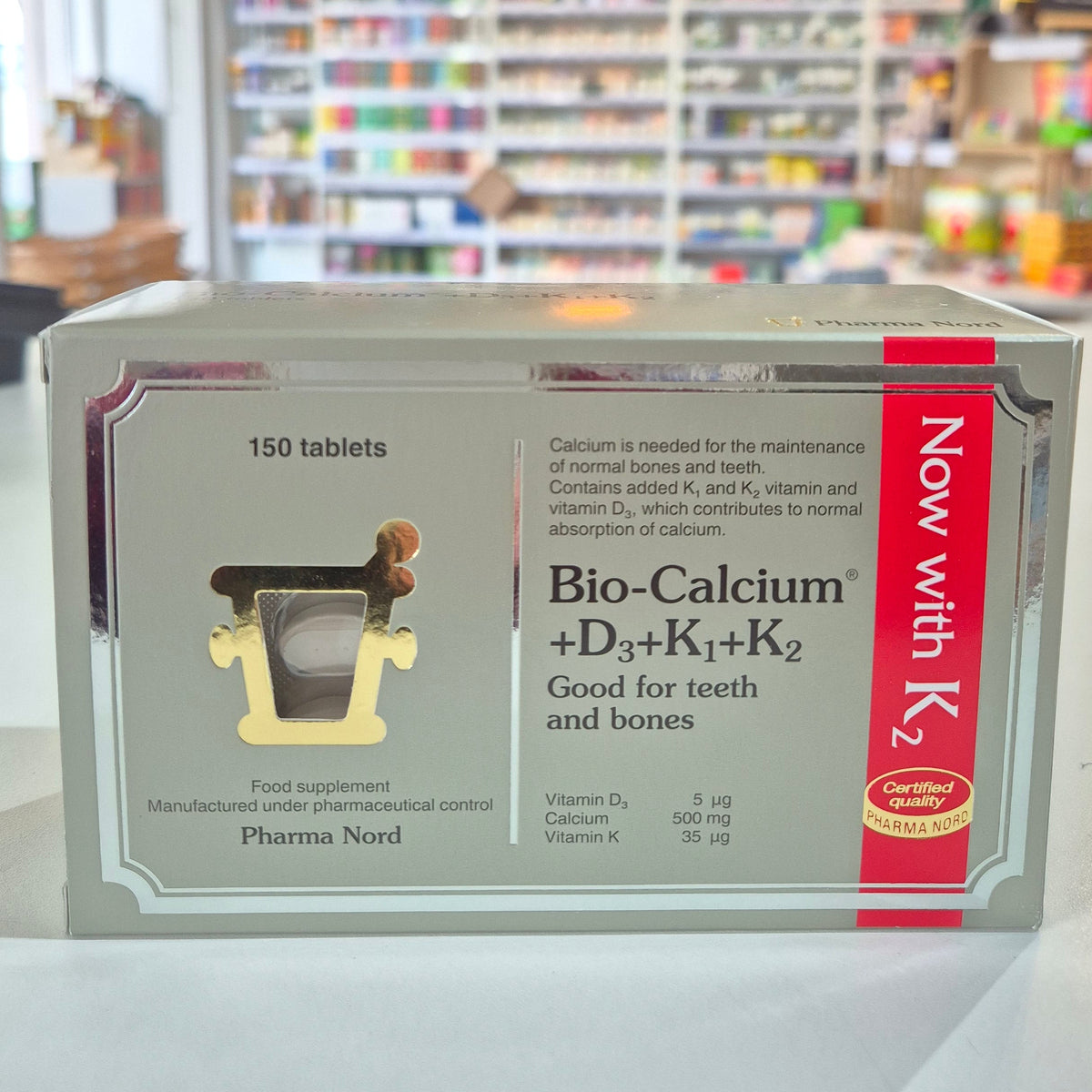 Box of Pharma Nord Bio Calcium + D3 - 150 Tabs with tablets displayed in front. 'Now with K2' on a shelf in a store.