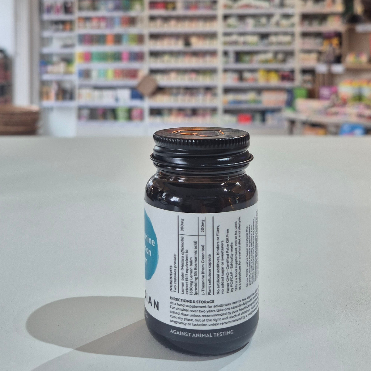 Brown glass bottle with a label on a white surface, blurred shelves in the background