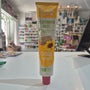 A tube of Tartex Vegetarian Pate Classic spread, featuring a yellow and white label with a sunflower graphic, lying on a white surface with a blurred store background.