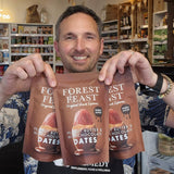 Man holding three packages of Forest Feast snack mix in a store setting