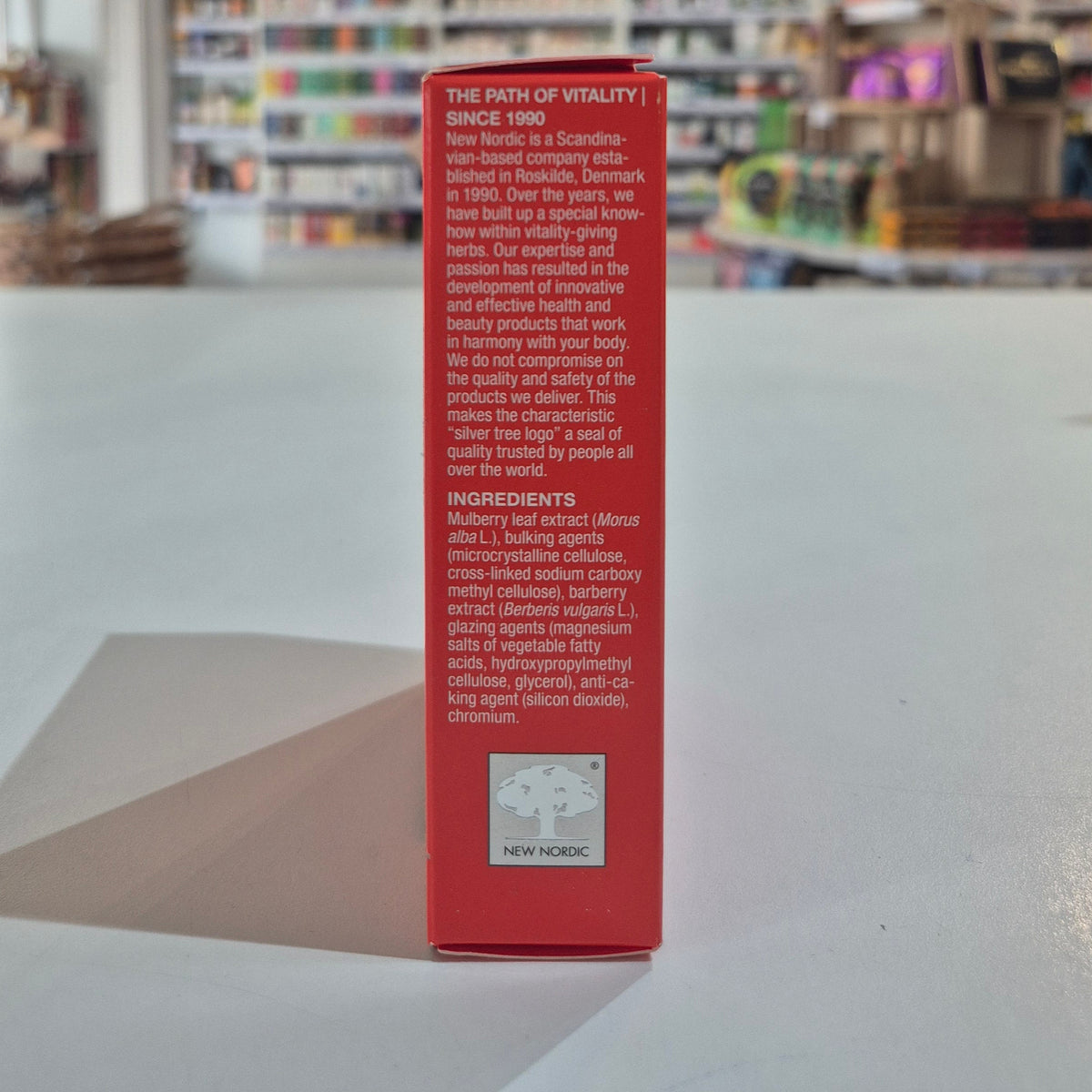 Red box with text and New Nordic logo on a blurred store shelf background
