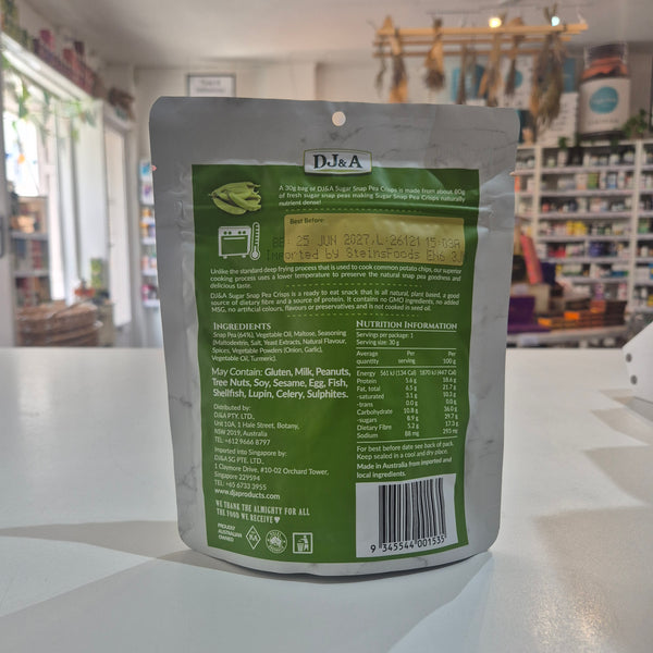 The back of a silver stand-up pouch with a green label, showing product details, ingredients, and nutrition facts, photographed on a white surface with a blurred store interior in the background.