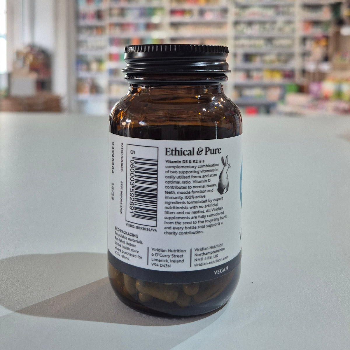 Brown bottle with a label on a white surface, blurred store shelves in the background