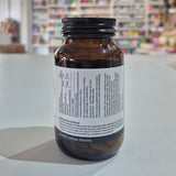 Brown supplement bottle with label on a white surface, blurred store shelves in the background