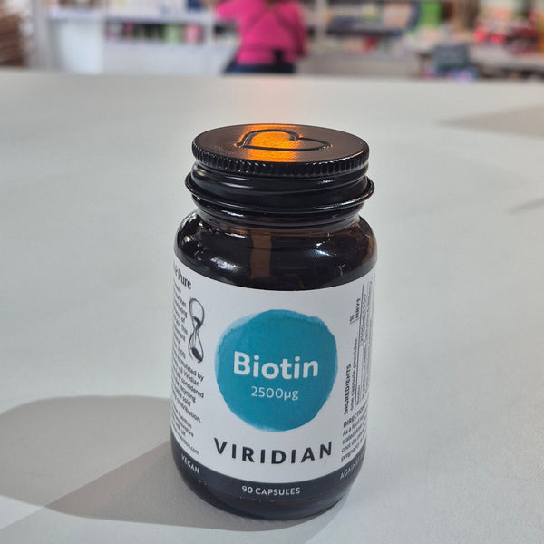 Bottle of Viridian Biotin on a white surface with a blurred store interior in the background.