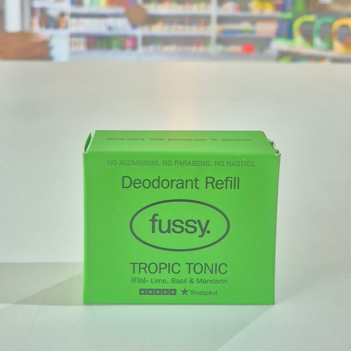 Green deodorant refill box labeled 'fussy' with a store shelf in the background